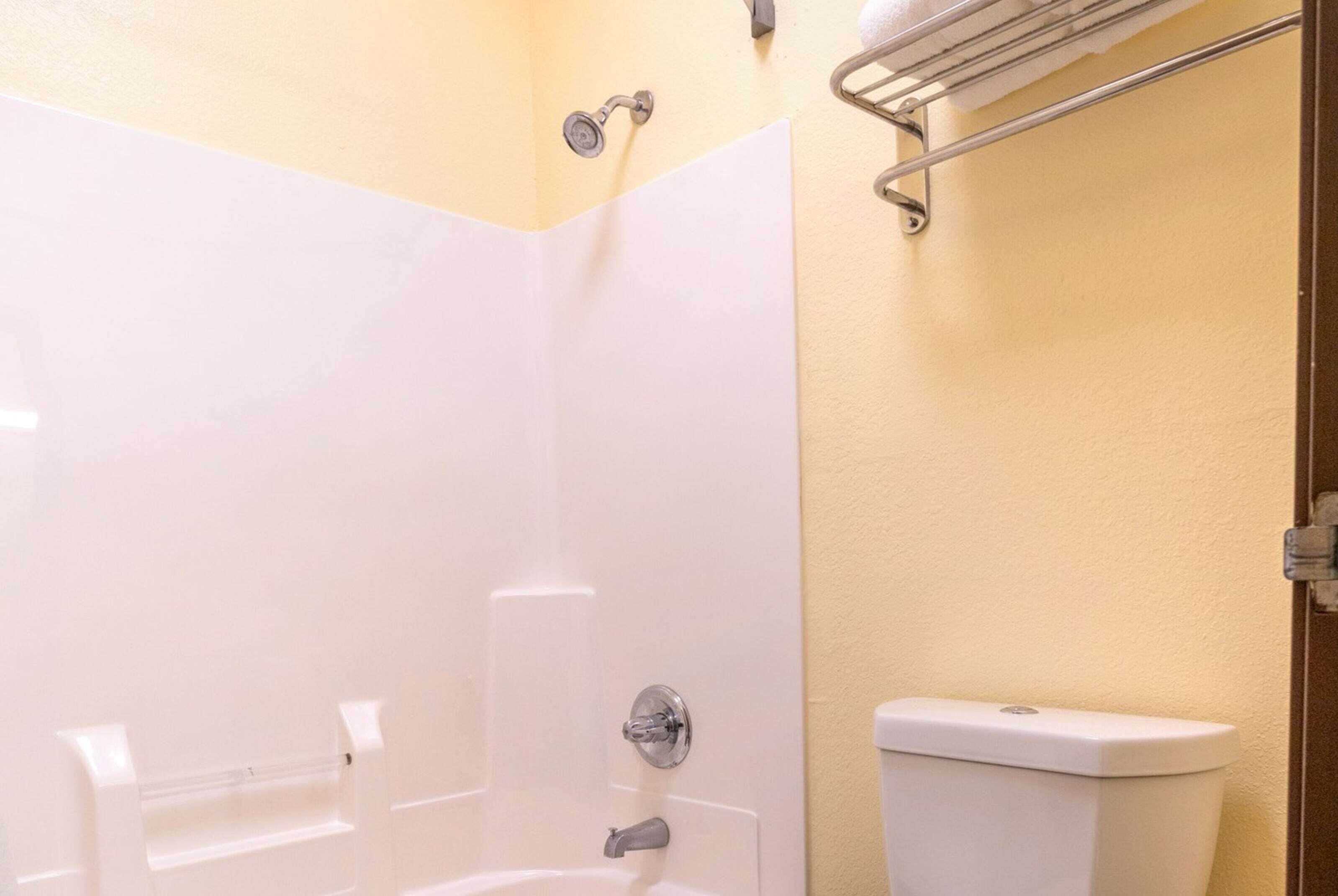 A bathroom with a bathtub, toilet, and a towel rack.