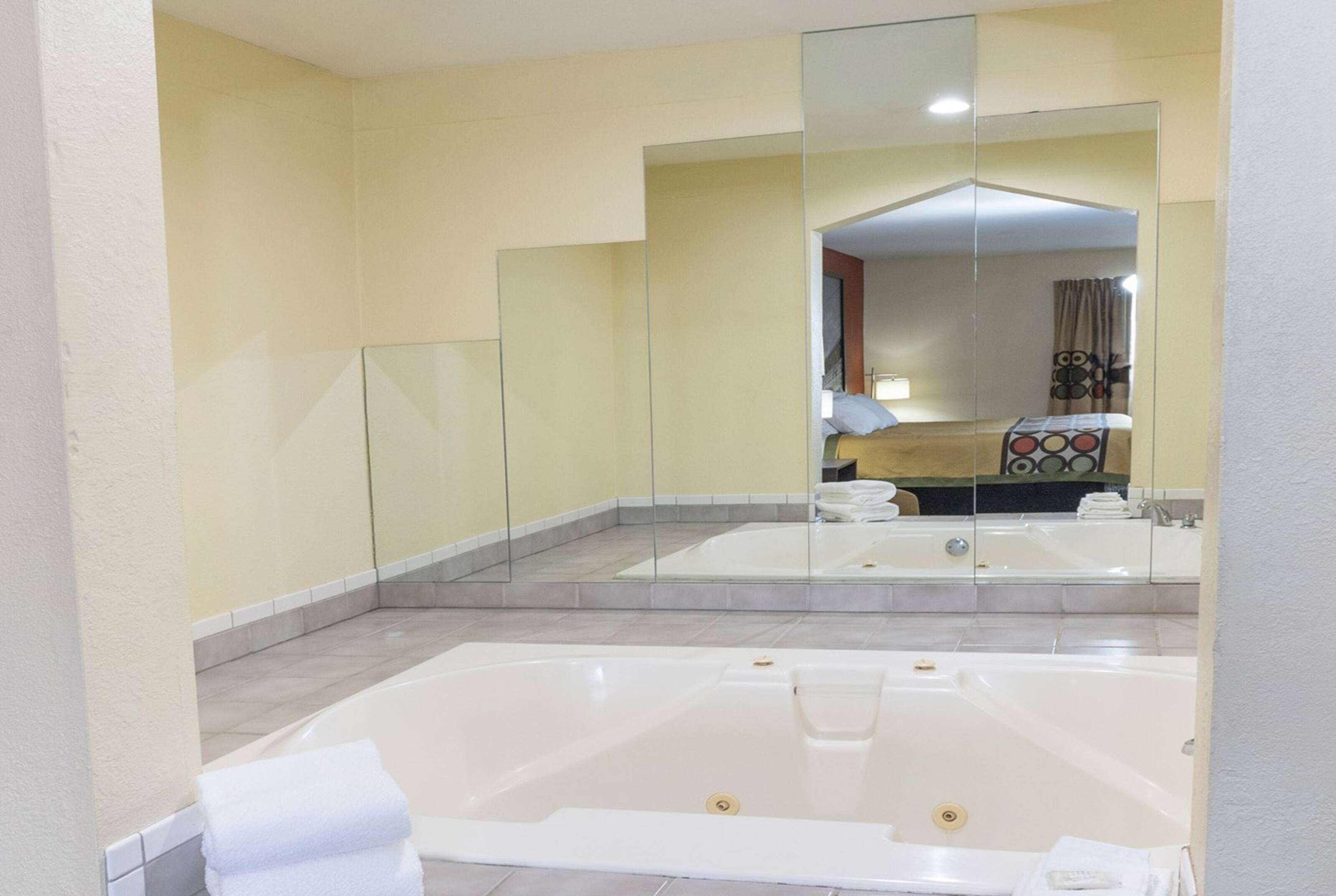 Een moderne badkamer met twee ruime badkuipen, een douchecabine met glazen wanden en een grote spiegel die de ruimte weerkaatst.