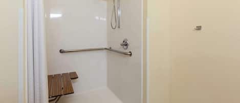 A shower area with a grab bar, a wooden bench, and a tiled floor.