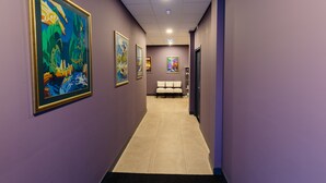 A hallway with framed artworks on the walls, a seating area with chairs, and a tiled floor. - Hotel De Looier (Amsterdam)