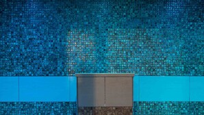 A bathroom with a mosaic tiled wall, a bench, and a shower area. - The Abbey Hotel Golf & Spa  (Redditch)