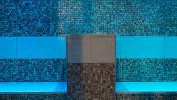 Bathroom features a central column with a sink and shower area, surrounded by a geometric tile design.