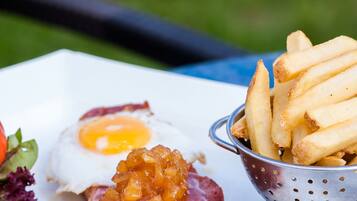 A plate with a ham slice topped with a fruit compote, a fried egg, and a side of fries.