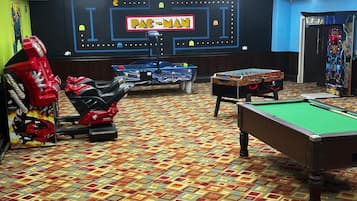 Una habitación con mesa de billar, mesa de fútbol de mesa y un juego de Pac-Man.