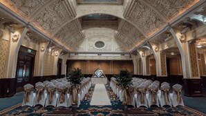 A grand hall with ornate ceiling and chandeliers, a central aisle with rows of chairs, and a floral arrangement at the front. - The Imperial Hotel (Blackpool)
