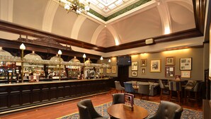 A bar area with a long counter, bar stools, and a round table with chairs. - The Imperial Hotel (Blackpool)