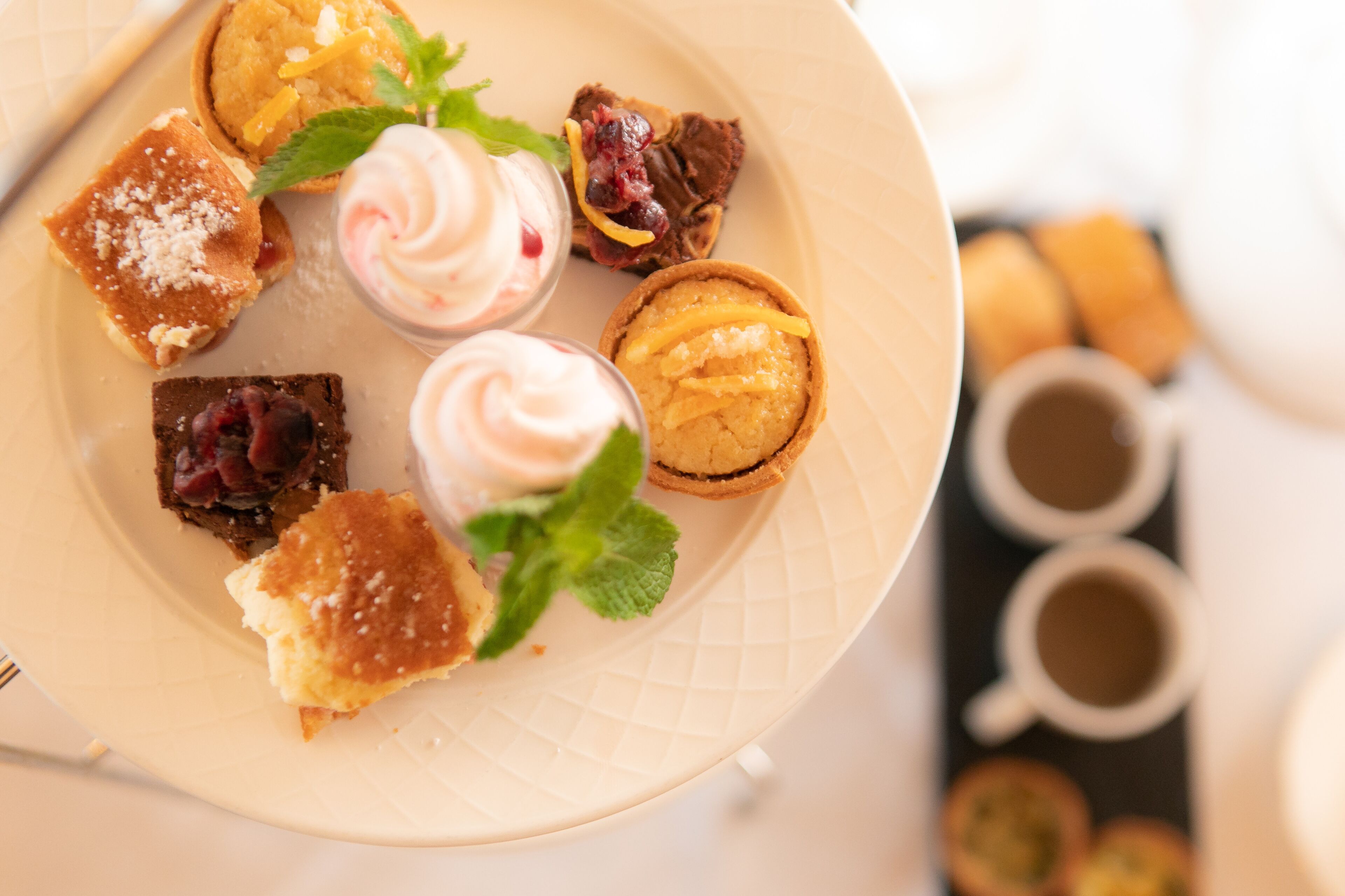 A plate with various desserts and a cup of coffee.