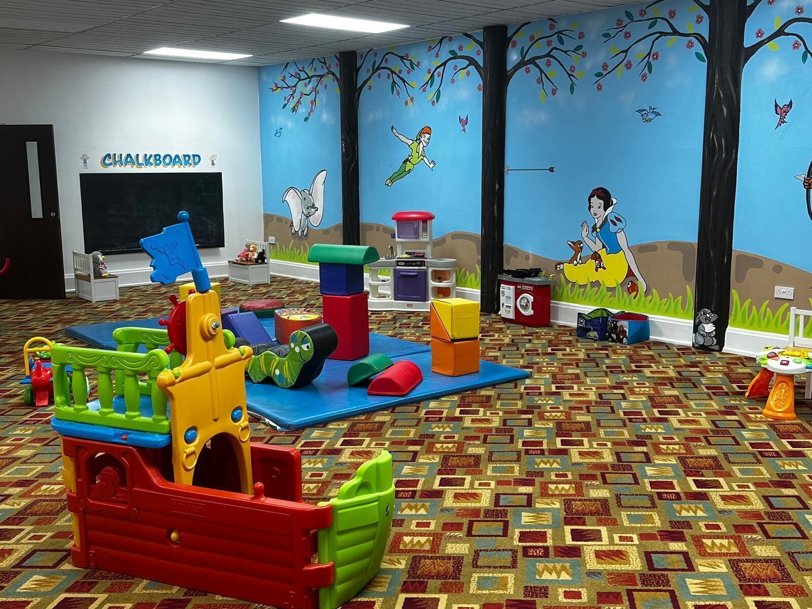 A children's play area with colorful toys and a chalkboard wall.