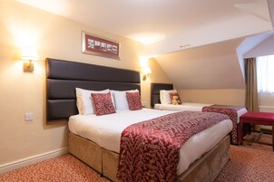 Een hotelkamer met twee bedden, een rood beddegoed met patroon, een hoofdeinde en twee wandlampen.