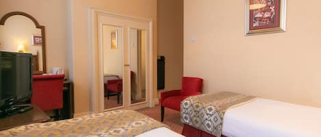 Habitación de hotel con dos camas, un televisor, un espejo y una silla roja.