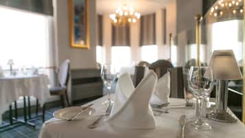 A dining table set with white tablecloth, silverware, and a wine glass.