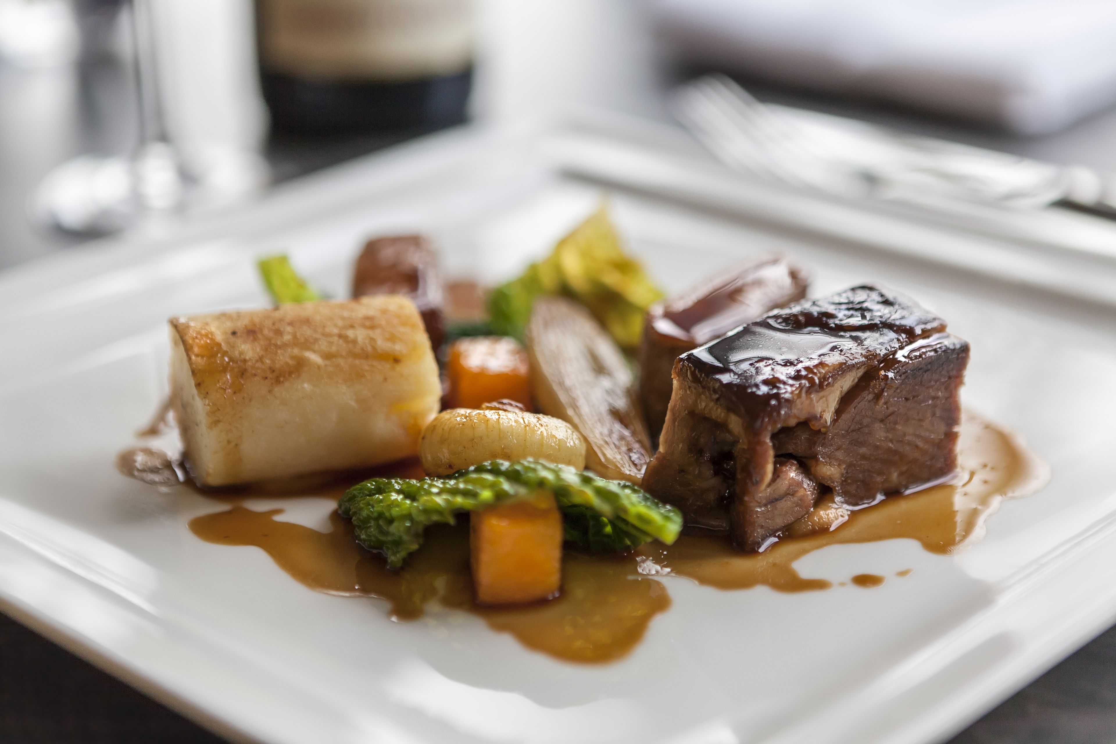 A plate of food with a piece of meat, vegetables, and a sauce.