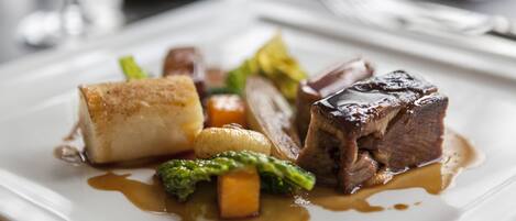 A plate of food with a piece of meat, vegetables, and a sauce.