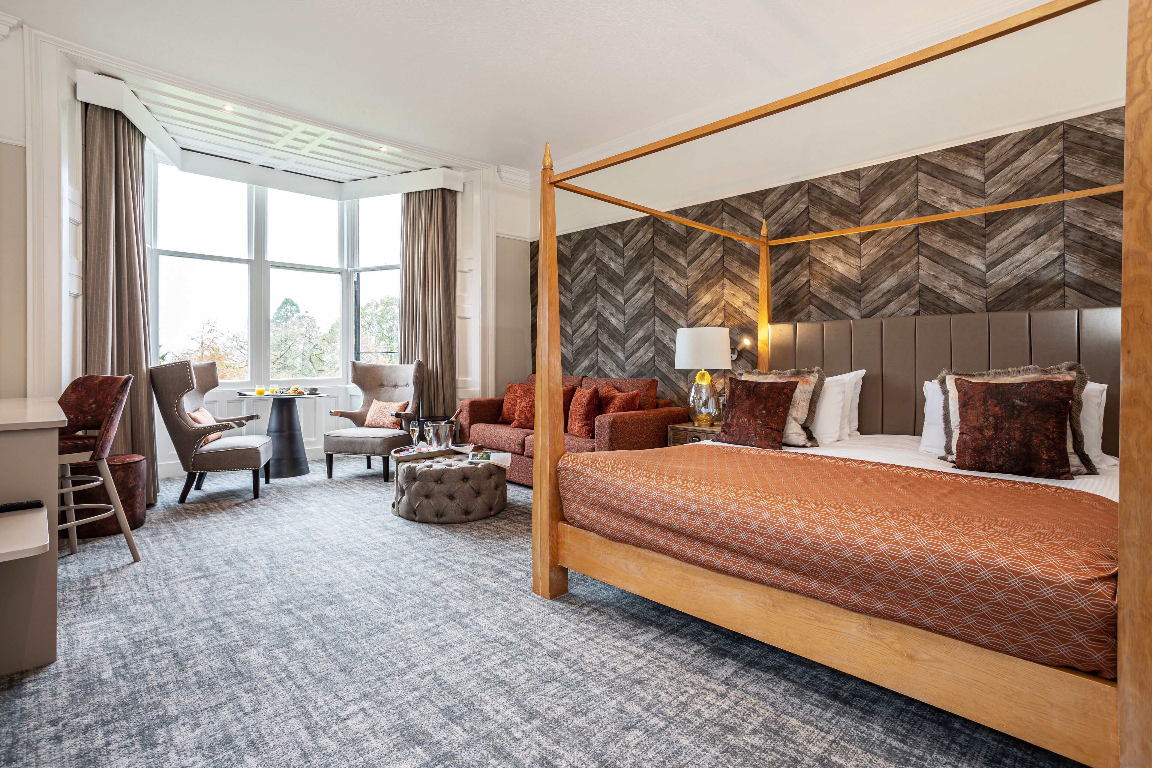 Ein Hotelzimmer mit Himmelbett, einer Couch, einem Schreibtisch und einem Sessel.