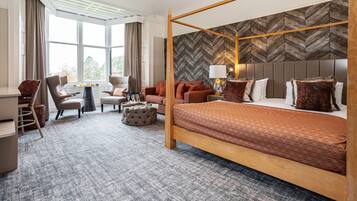 Ein Hotelzimmer mit Himmelbett, einer Couch, einem Schreibtisch und einem Sessel.