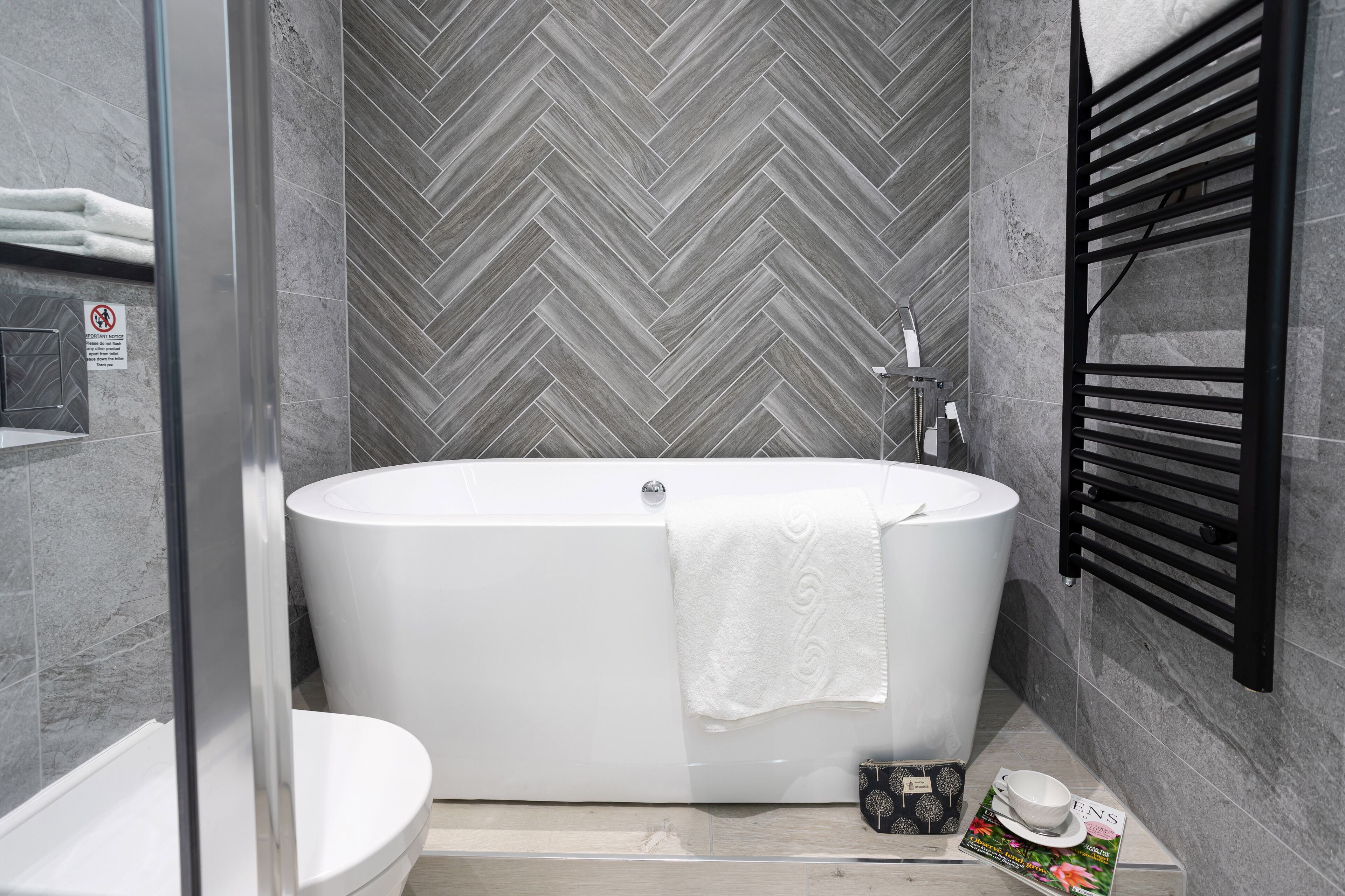 A modern bathroom with a freestanding bathtub, a glass shower enclosure, and a towel rack.