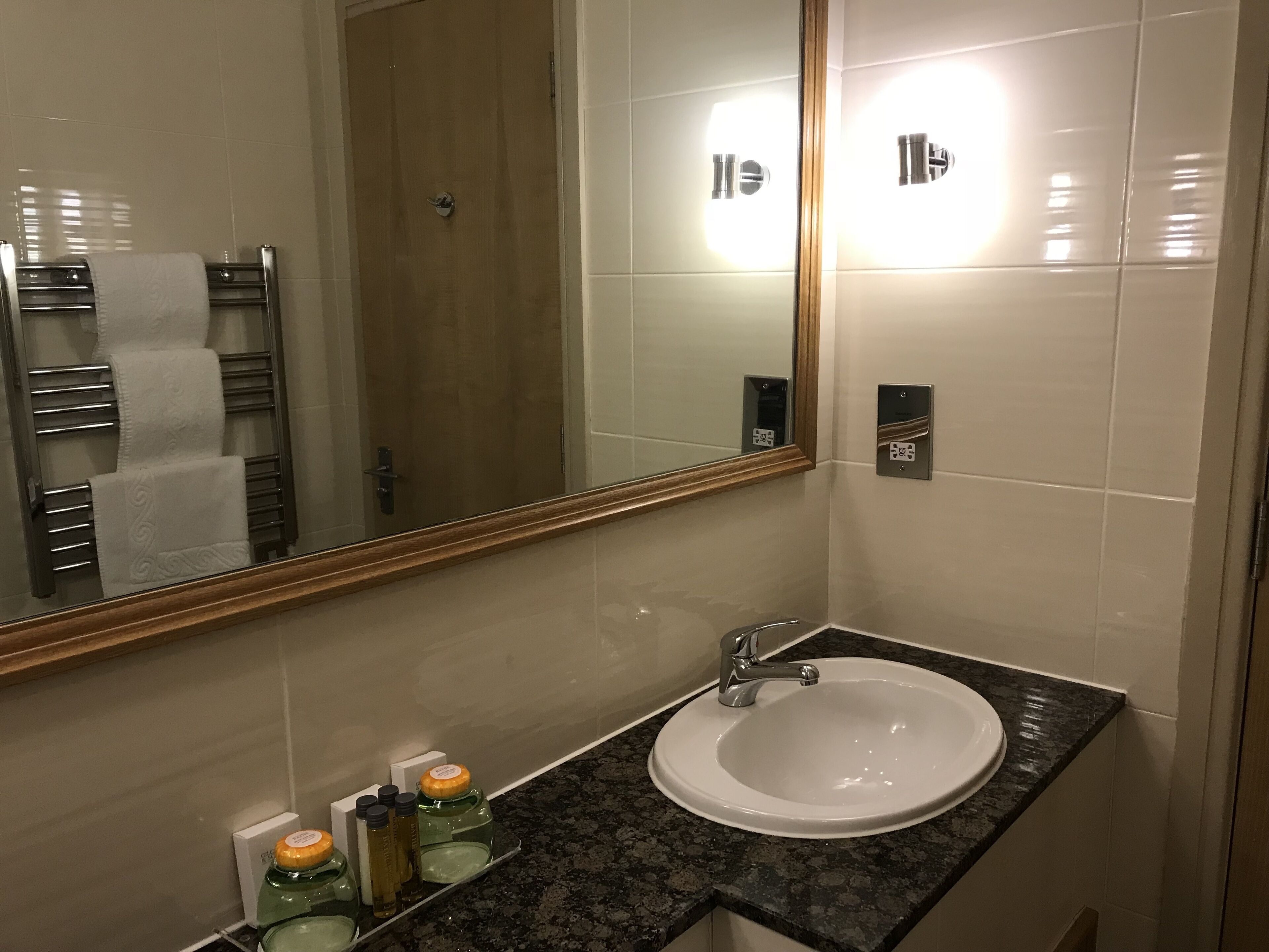 A bathroom with a white sink, a mirror, and a towel rack.
