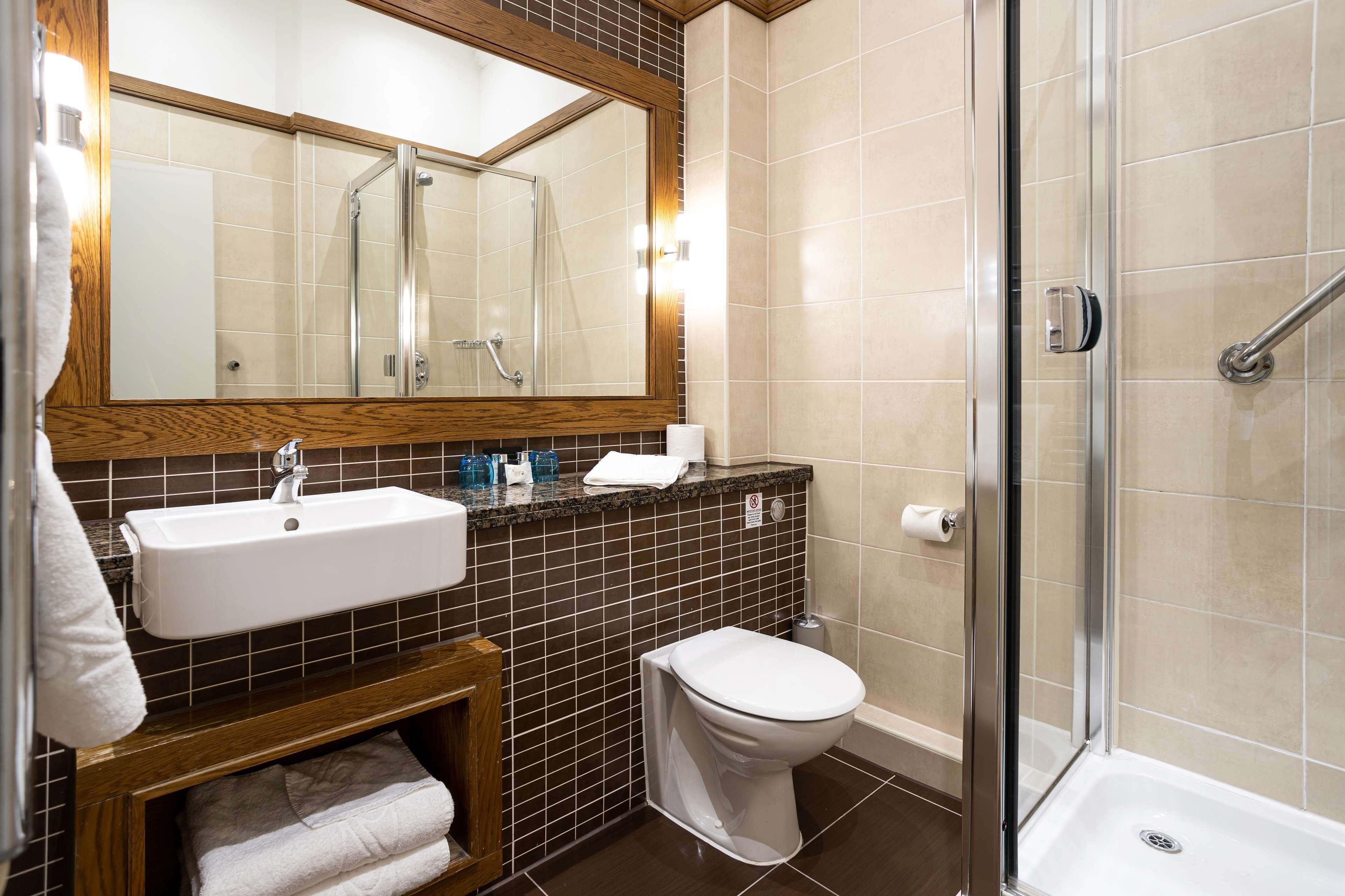 Et badeværelse med håndvask, toilet og bruseområde.