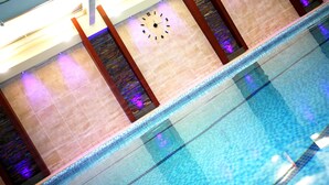 En swimmingpool med en klocka på väggen, omgiven av kaklade väggar och träpelare.