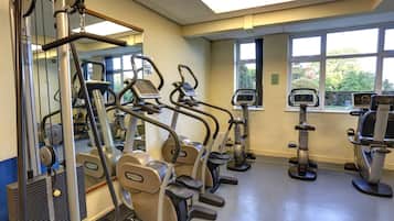 Un gimnasio con cintas de correr, elípticas y máquinas de pesas.