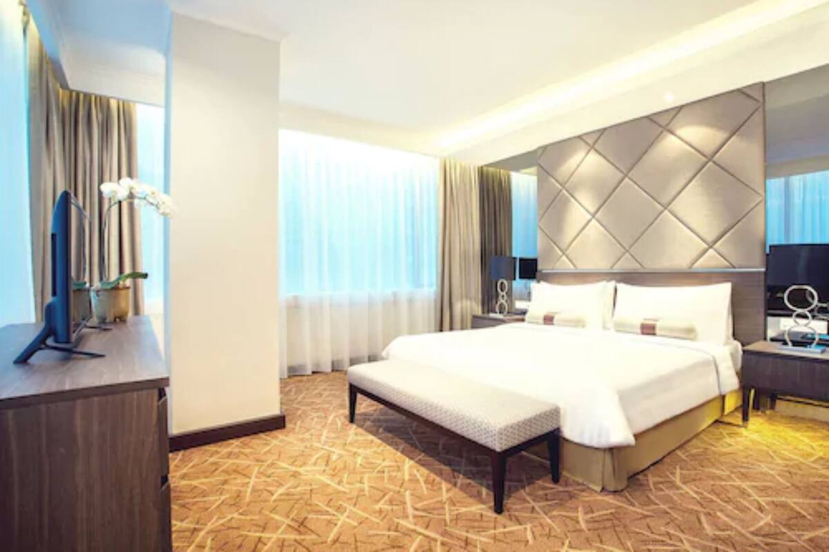 Une chambre d’hôtel moderne, dotée d’un grand lit, d’un bureau et d’une télévision.