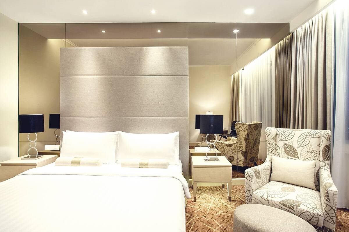 Une chambre d’hôtel avec un grand lit, deux tables de chevet, une chaise et un canapé.