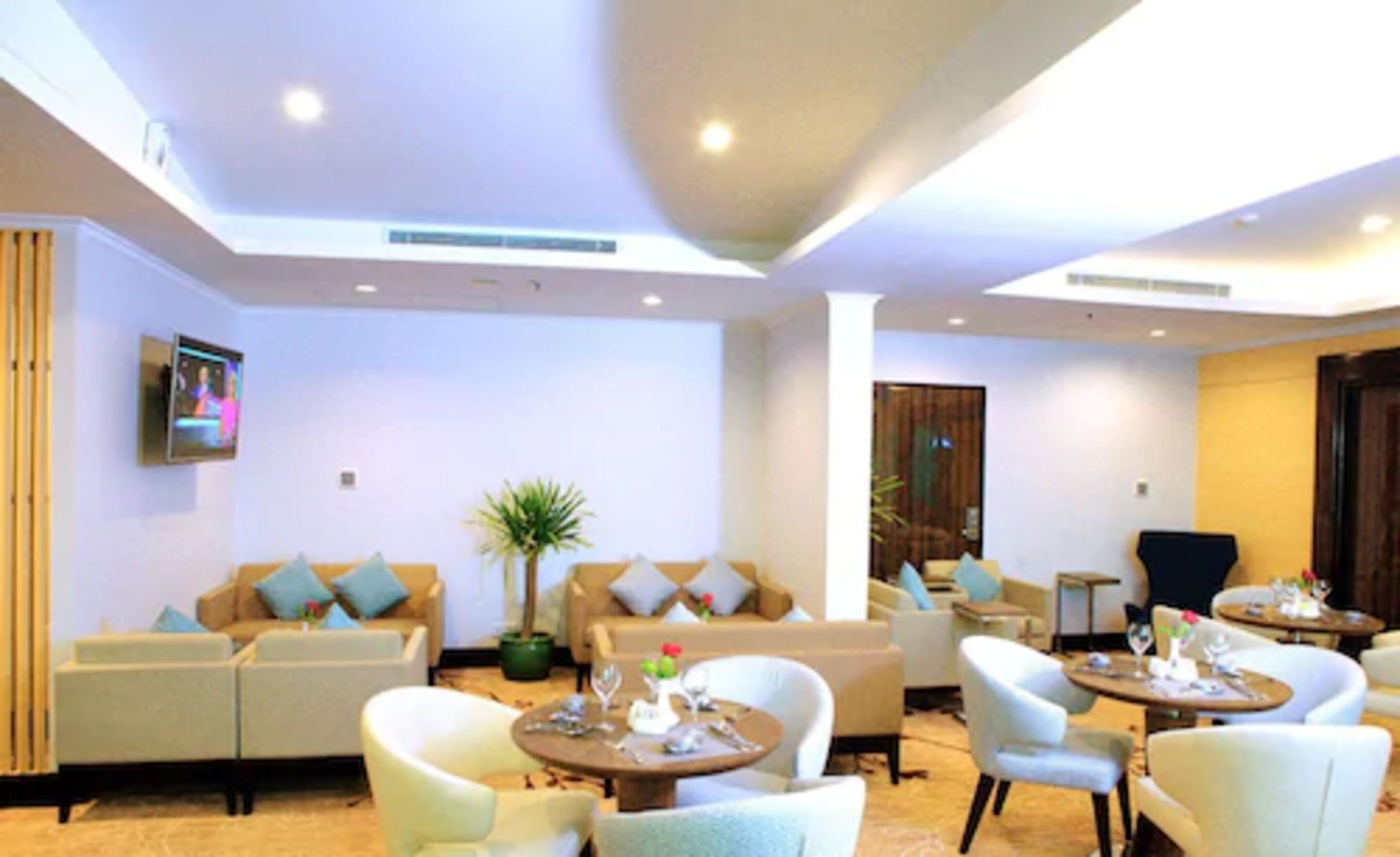 A spacious lobby with multiple seating areas, including sofas and armchairs, and a television mounted on the wall.