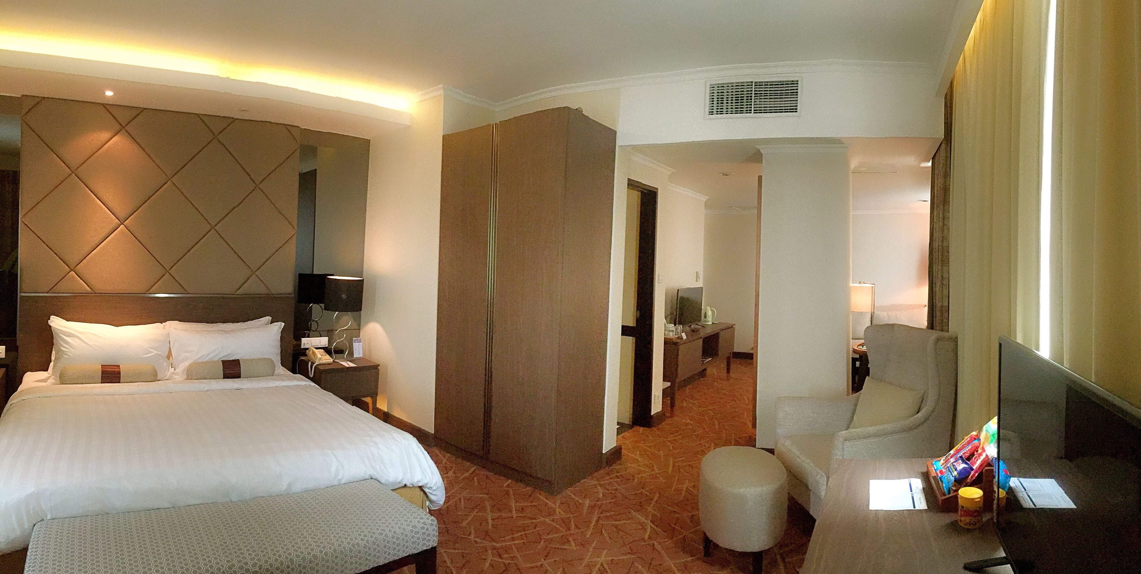 A hotel room with a large bed, a desk, a chair, and a television.