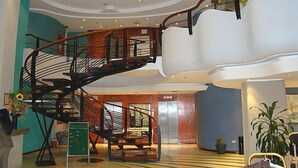 Un intérieur moderne avec un escalier en colimaçon, une grande structure blanche évoquant un nuage et un plancher en bois.