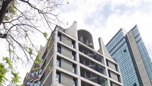 Un immeuble à plusieurs étages avec une entrée de garage, un drapeau et une enseigne indiquant qu’il s’agit d’un hôtel.