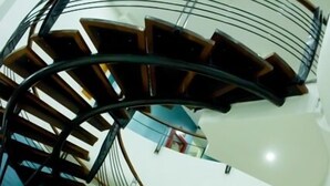 Un escalier en colimaçon avec des marches en bois et des rampes en métal, situé dans un espace int érieur moderne.