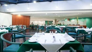 Un restaurant spacieux avec des tables et des chaises vertes, des nappes blanches et un décor intérieur moderne.