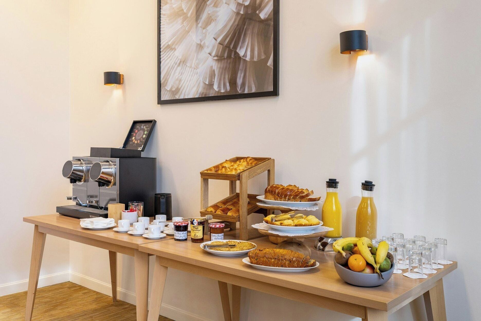 Un bufé de desayuno con cafeteras, pastelería, fruta y botellas de zumo.