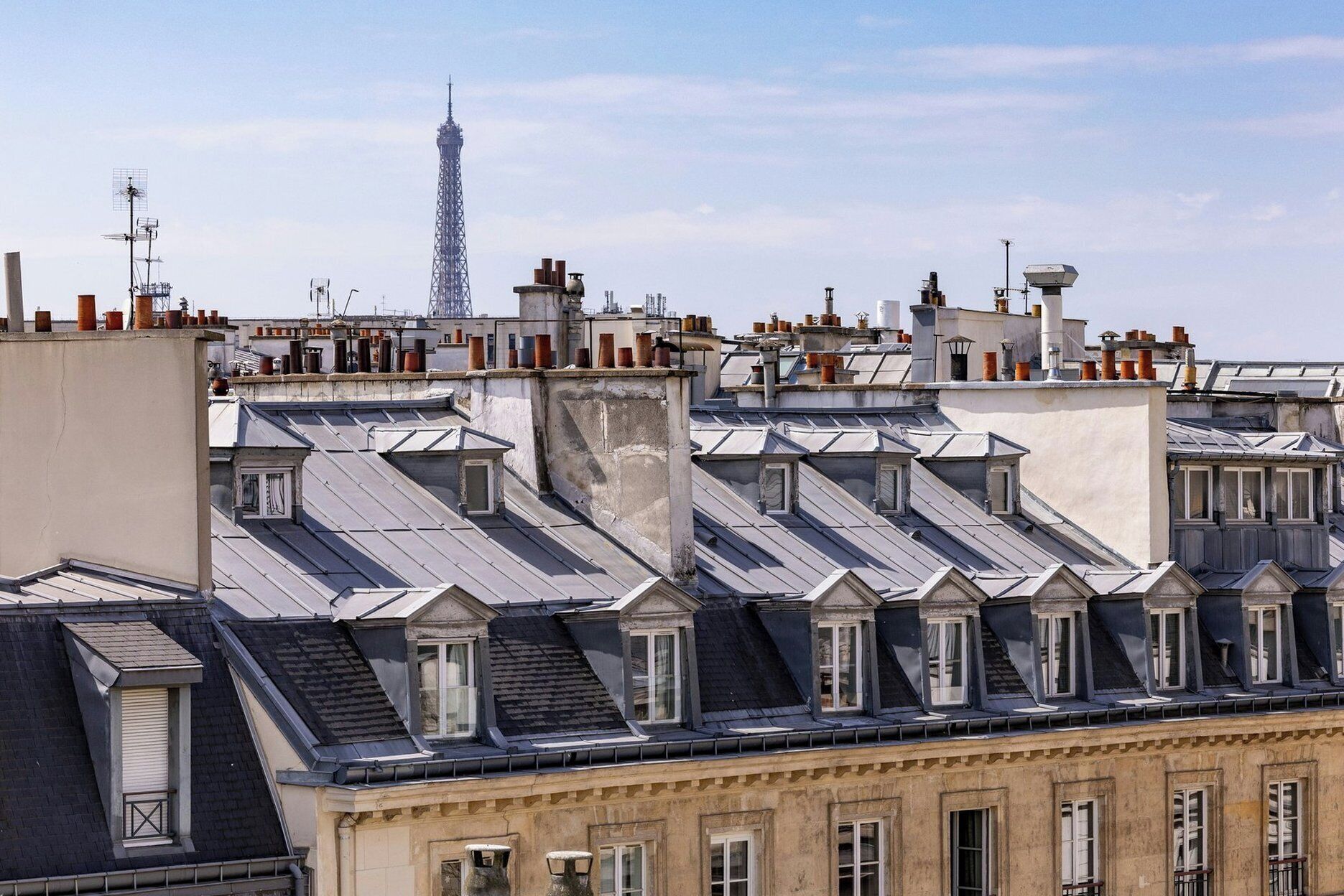 Una hilera de edificios con techos empinados y ventanas salientes, característicos de la arquitectura parisina.
