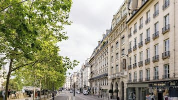 Una calle arbolada con edificios históricos, un hotel Citadines y una tienda llamada BONJOUR DE PARIS.