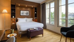 Une chambre d’hôtel comprenant un lit, un bureau avec une lampe, une chaise, une fenêtre avec vue et des étagères intégrées.