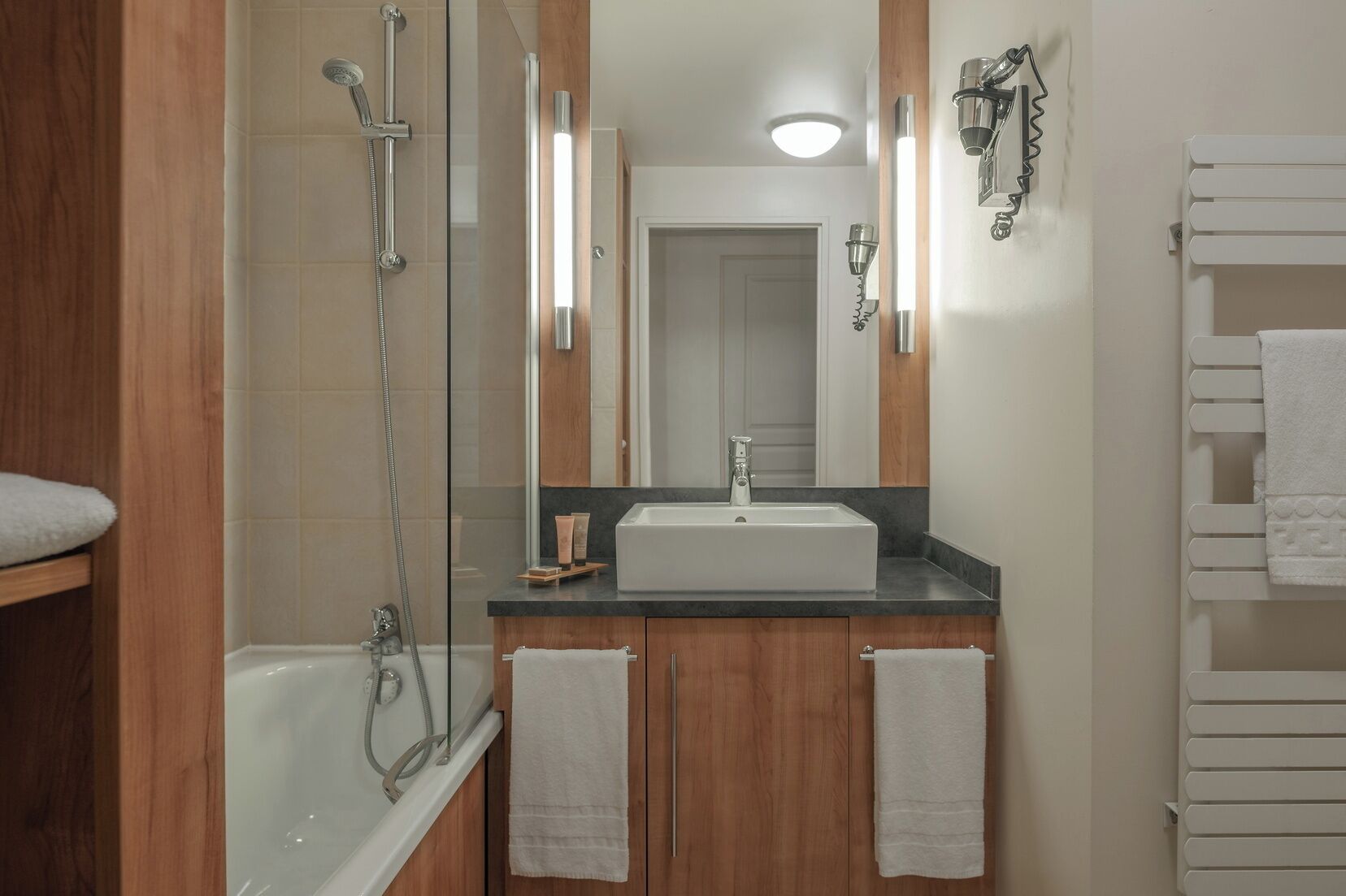 A modern bathroom with a glass-enclosed shower, a vanity with a sink, and a mirror.