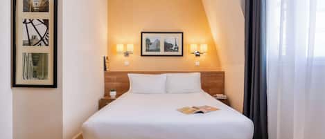 A hotel room with a large bed, two wall-mounted lamps, and framed pictures on the wall.