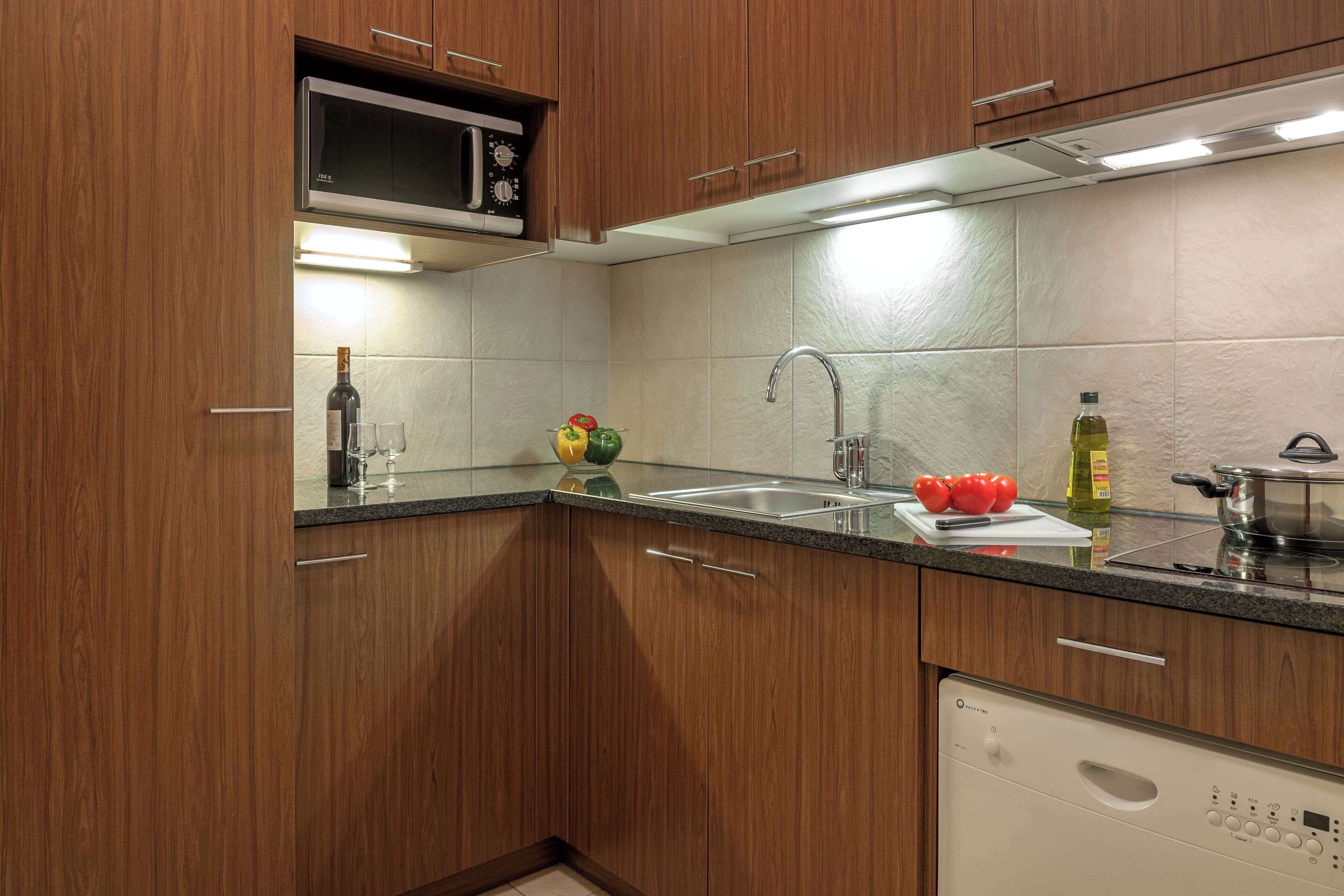 A modern kitchen with wooden cabinets, a stainless steel sink, and a built-in microwave.