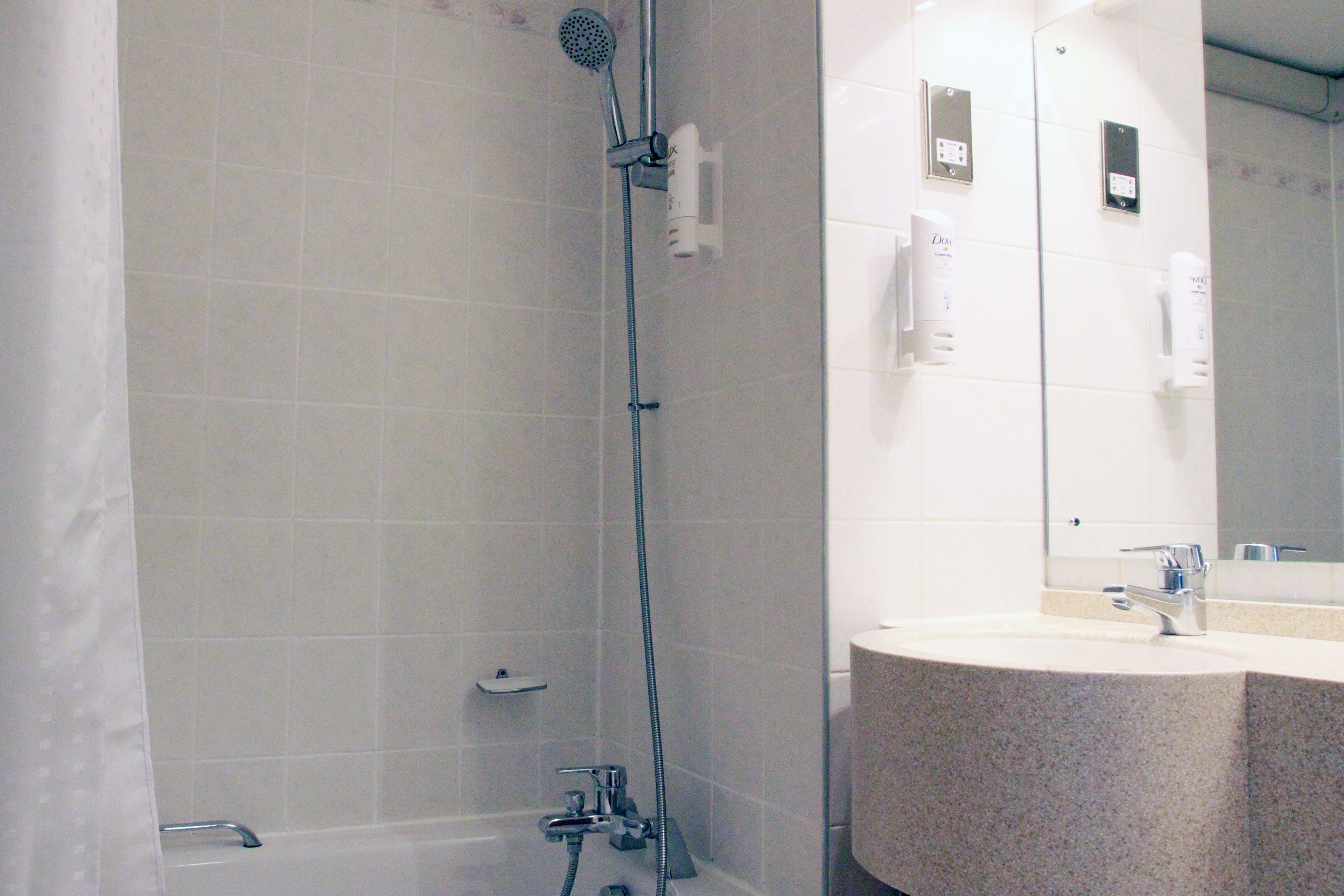 A bathroom with a shower, sink, and mirror.
