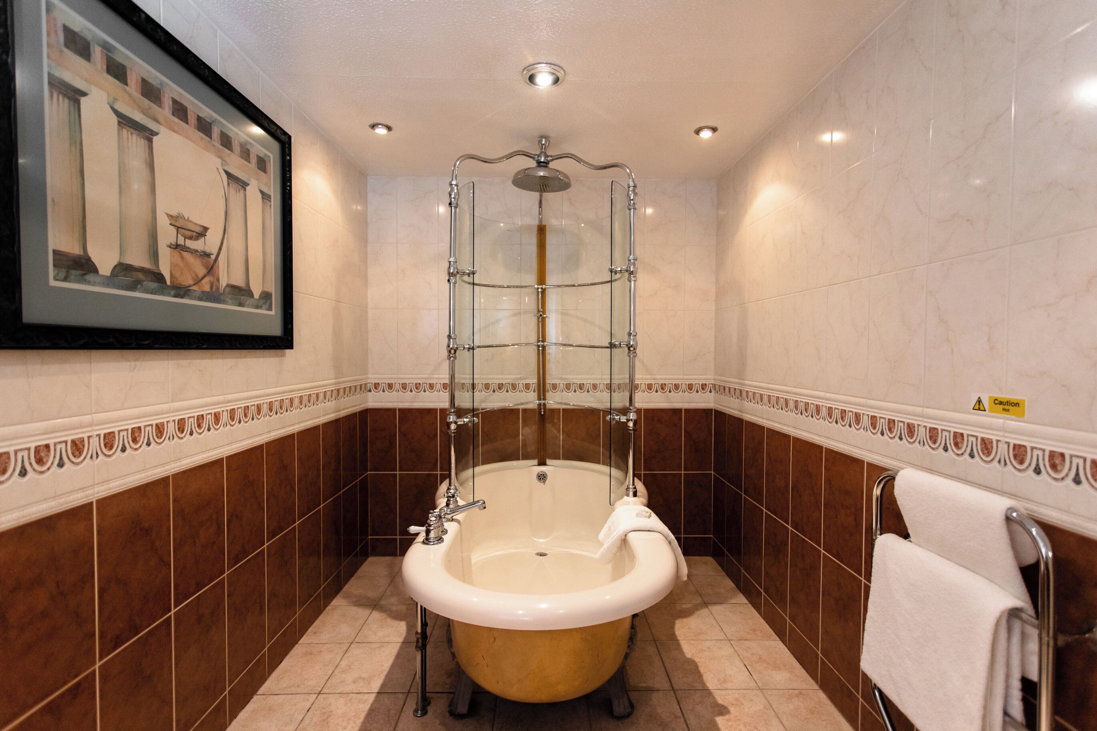 A bathroom with a freestanding bathtub, a framed picture on the wall, and a caution sign.
