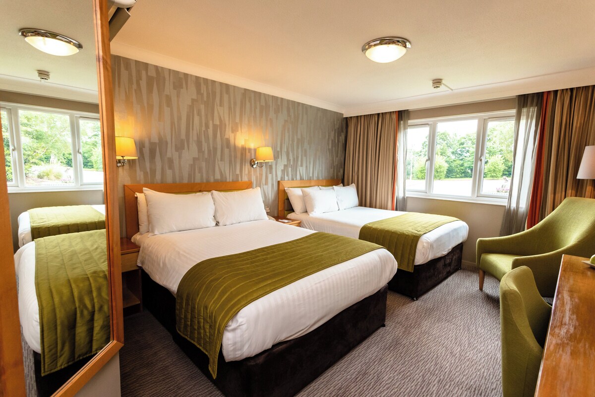 Une chambre d’hôtel avec deux lits, un bureau et une chaise.