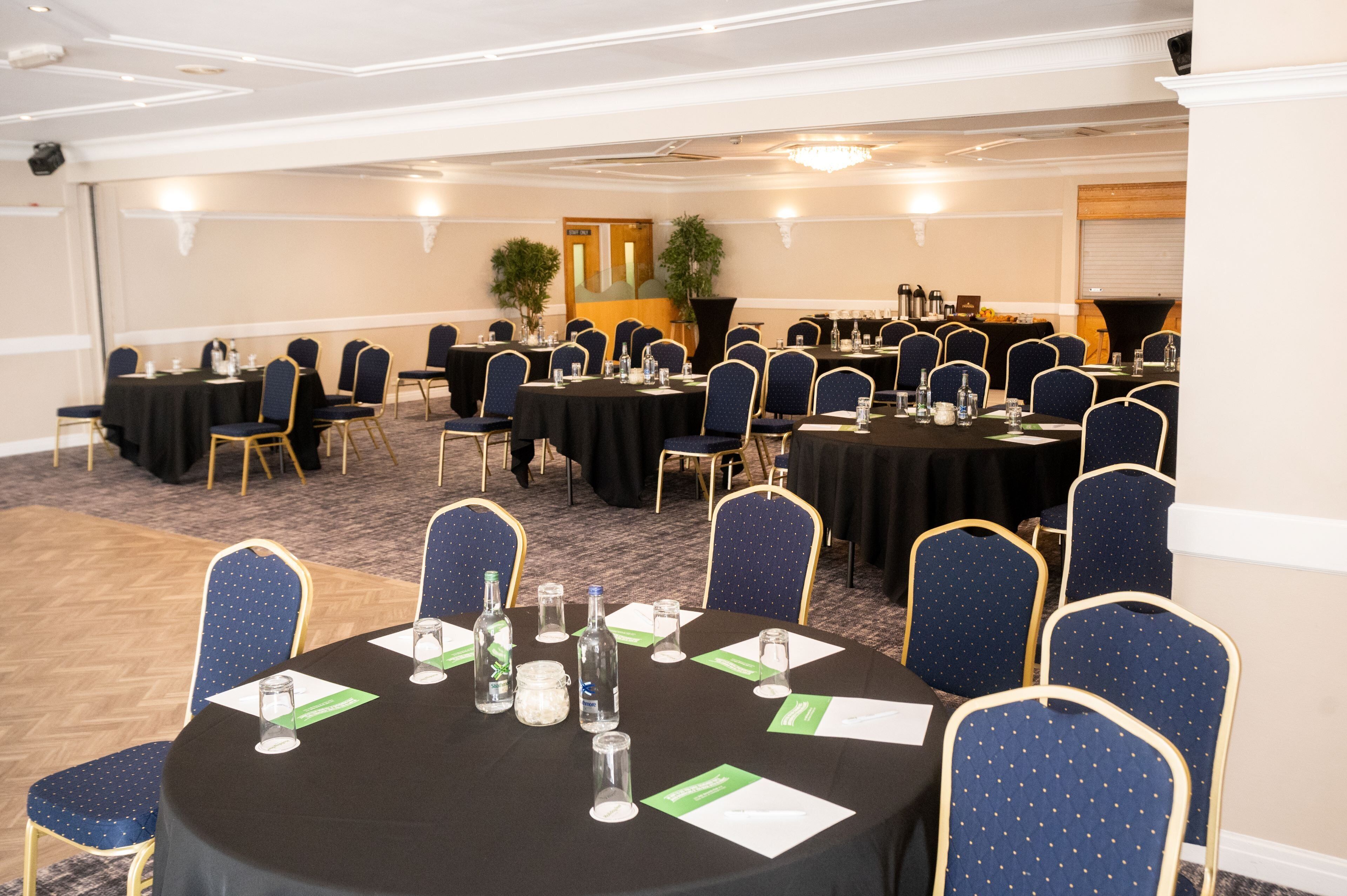 A conference room with multiple tables and chairs, equipped with nameplates and water bottles.