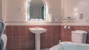 Un baño con lavamanos pedestal, un espejo encima, inodoro y bañera.