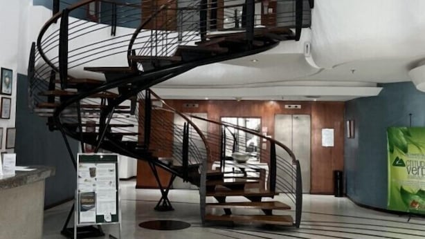 A modern interior with a spiral staircase, a reception desk, and a large white cylindrical sculpture. - Caracas Cumberland  (Caracas)