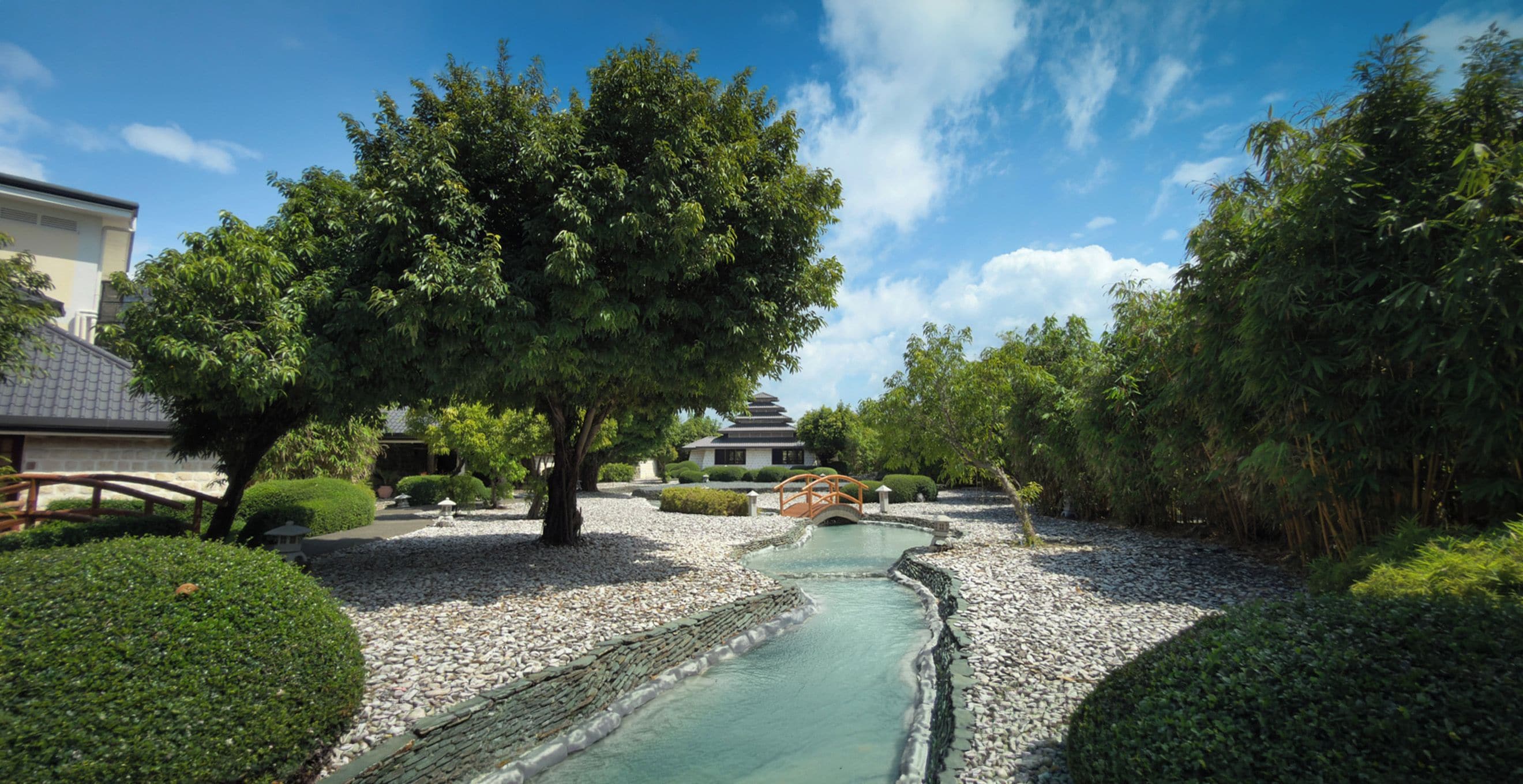 A traditional Japanese garden with a stone bridge, a koi pond, and a pagoda.