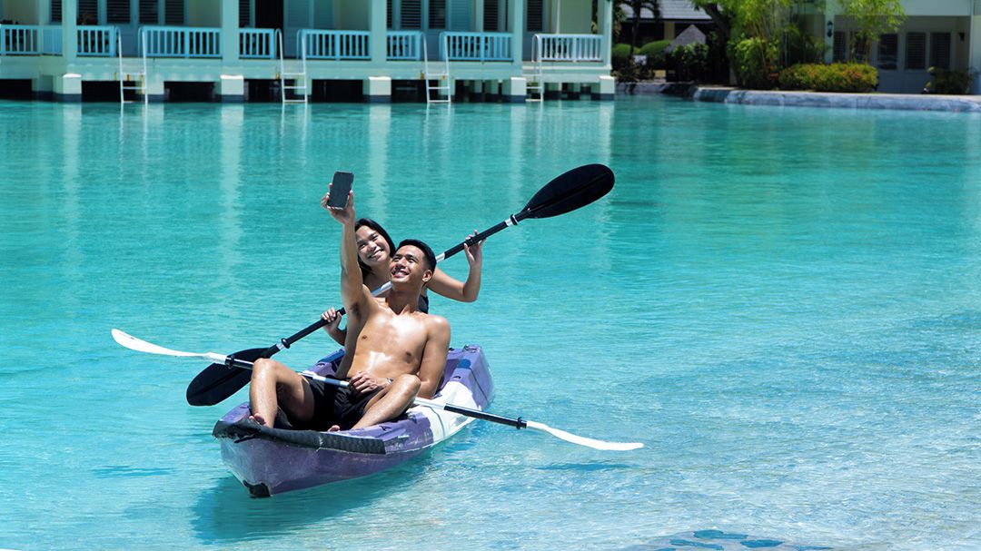 Two people in a small boat with paddles, floating on a clear pool.