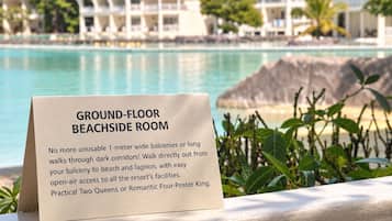 A sign for a ground-floor beachfront room with a view of resort buildings and a pool.