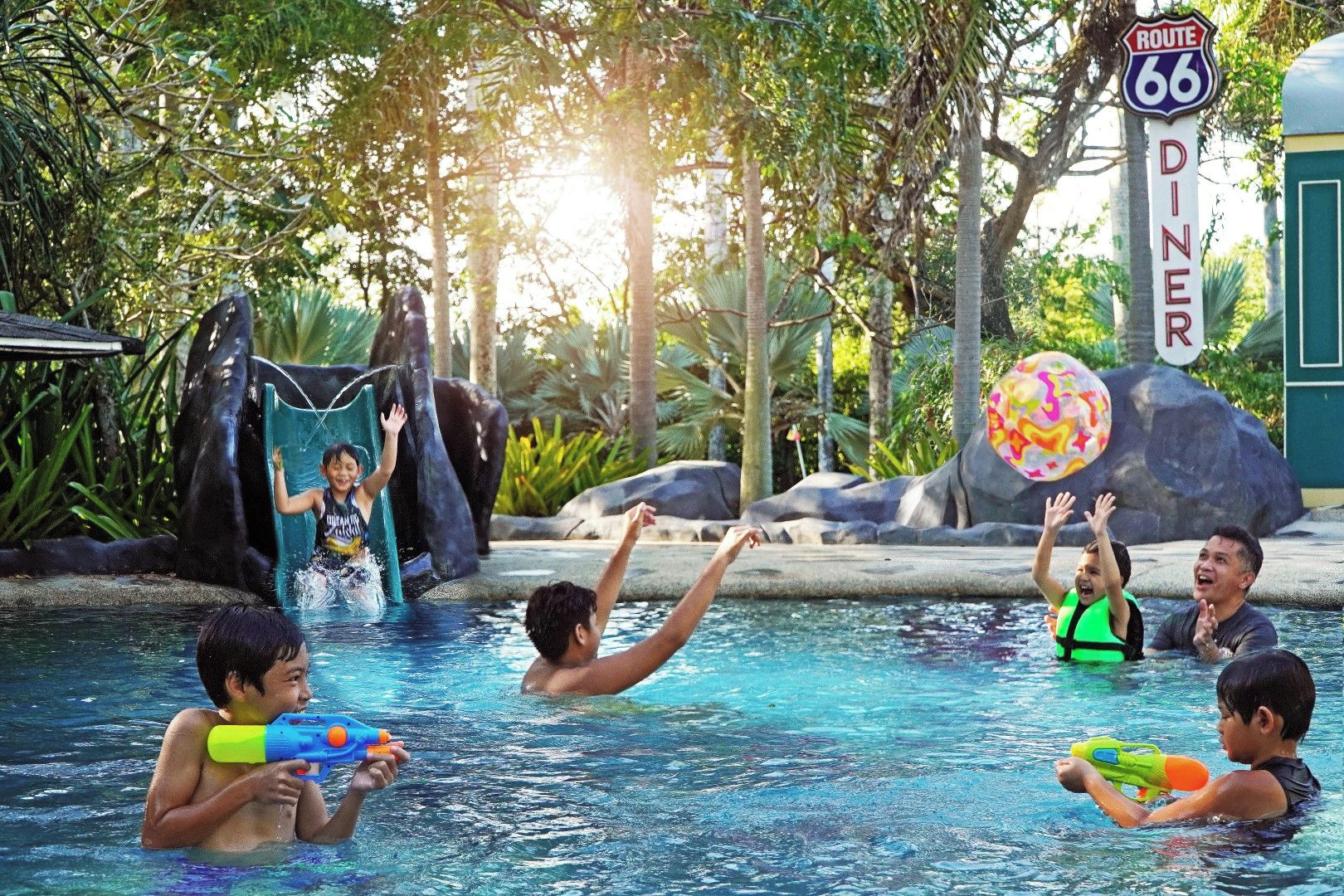 A pool area with a water slide, a diner's sign, and a Route 66 sign.