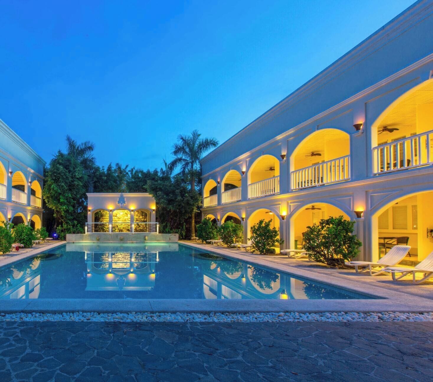 Un complejo turístico con piscina central, varios balcones y un área exterior bien iluminada.
